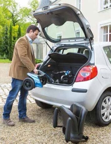 A man storing a mobility scooter in the boot of a car