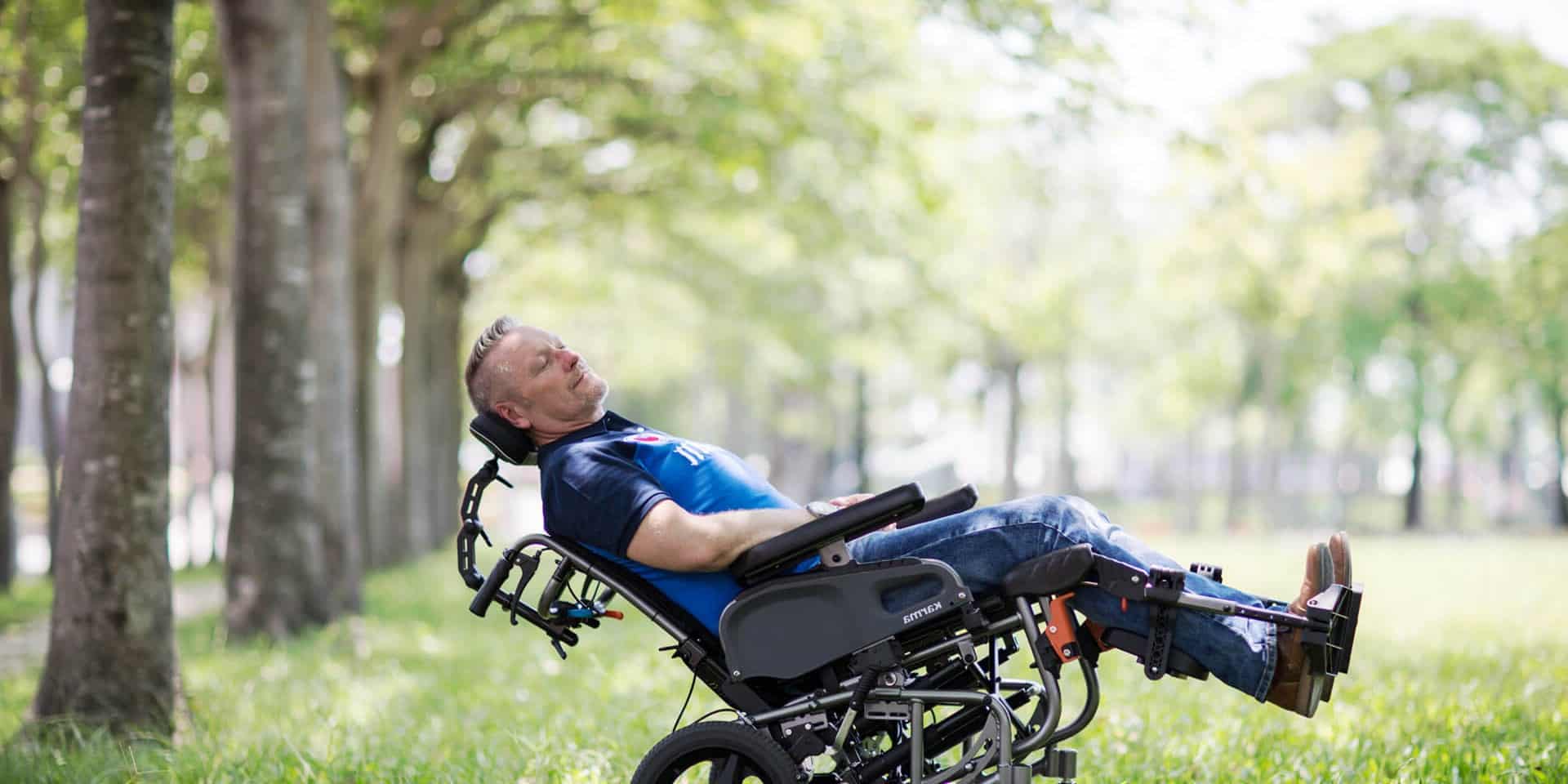 a man in a park using a lightweight folding electric powered mobility scooter front